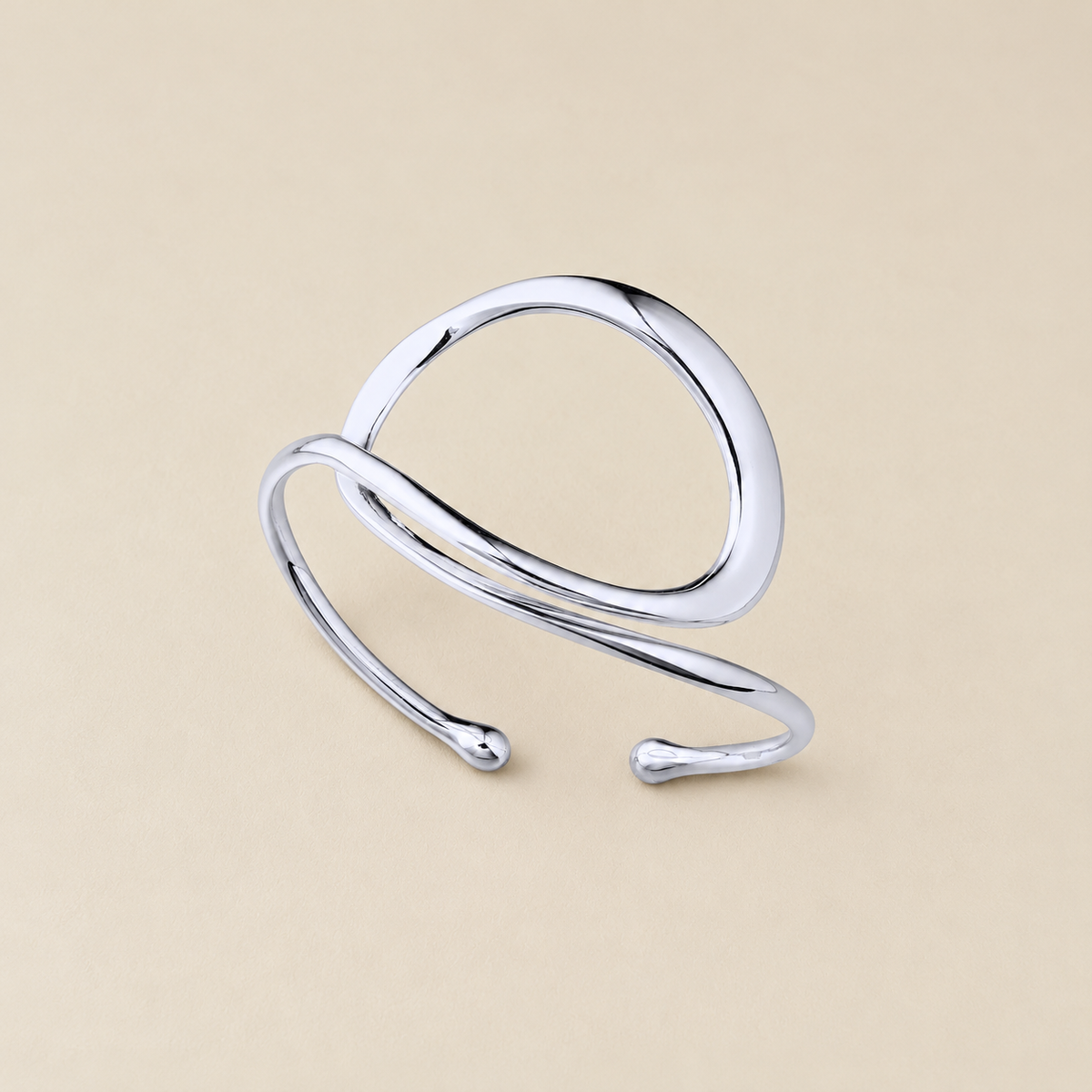A polished silver open cuff ring with a modern, flowing organic loop design, shown on a solid beige background.