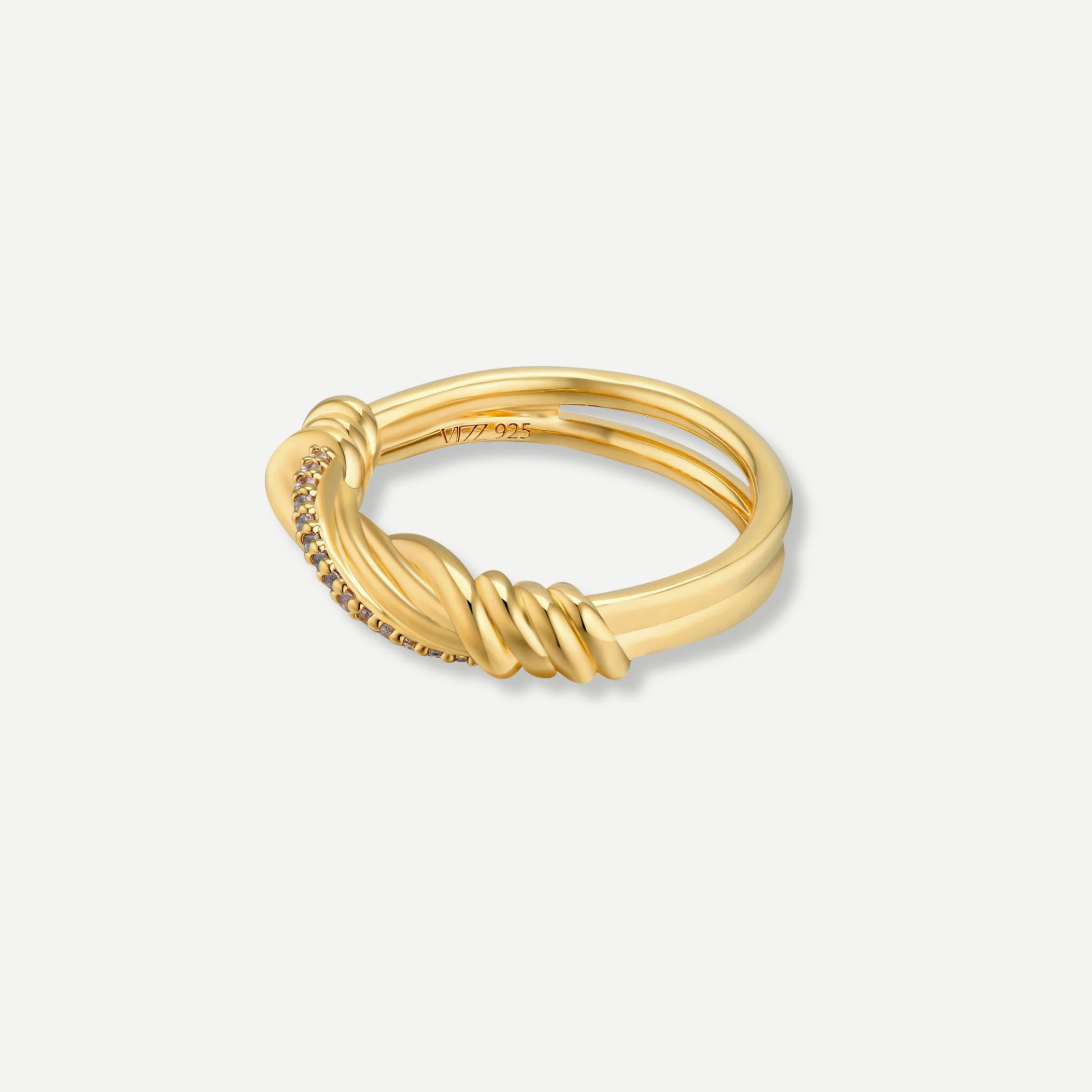 Gold ring with intricate design on a light gray background
