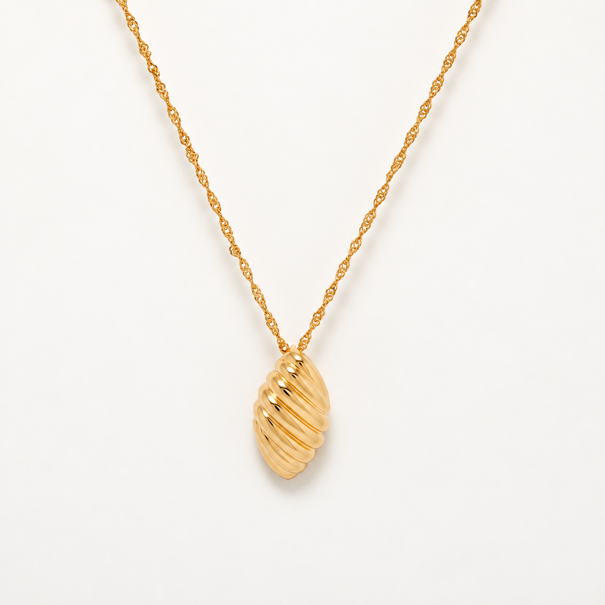 A gold necklace with a textured, ribbed shell-shaped pendant on a delicate twisted chain, photographed against a clean white background.