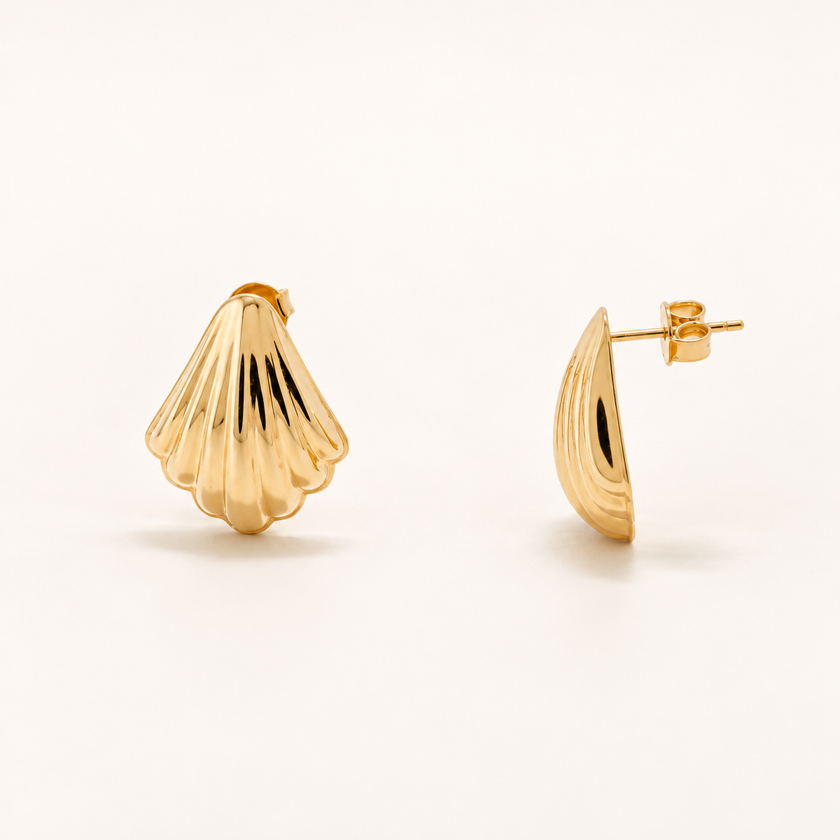 A pair of gold stud earrings shaped like a scallop shell, shown from both front and side angles on a clean white background.