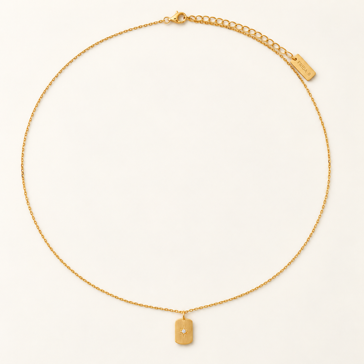 A delicate gold chain necklace with a small rectangular pendant and an adjustable chain extension, displayed on a clean off-white background.
