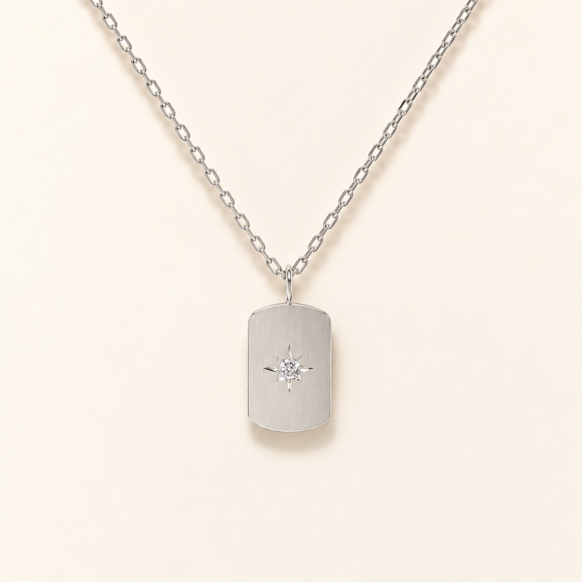 Stella Pendant Necklace in silver: brushed rectangular tag with a star-set stone, close-up on ivory.