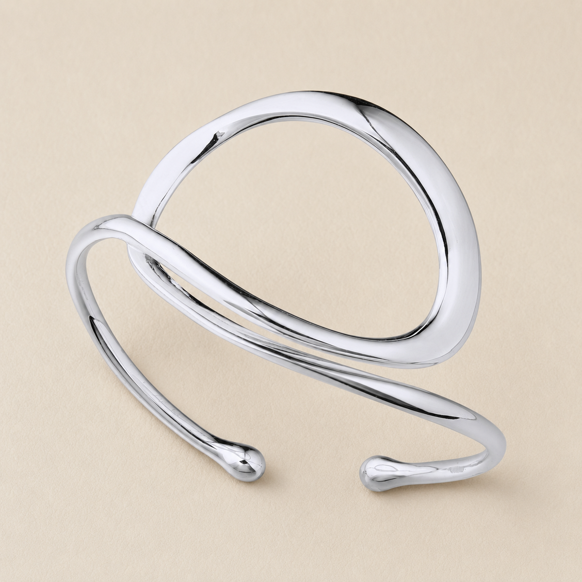 A polished silver open cuff ring with a modern, flowing organic loop design, shown on a solid beige background.